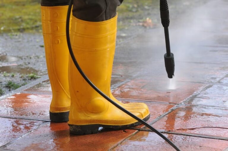 A professional cleaner using a low-pressure washer to clean a house's exterior.